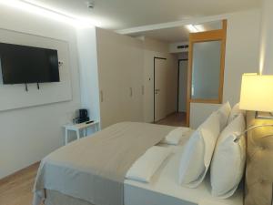 a white bedroom with a large bed and a flat screen tv at Gartenhotel Altmannsdorf in Vienna +57 photos