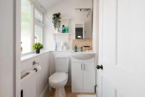 a white bathroom with a toilet and a sink at Modern House By LiveStay Short Lets & Serviced Accommodation Luton With Private Garden, BBQ & Free WiFi in Luton +26 photos