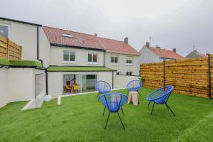 three chairs and a table in the yard of a house at Le Cosy - Appartement avec Jardin Wimille proche Wimereux in Wimereux
