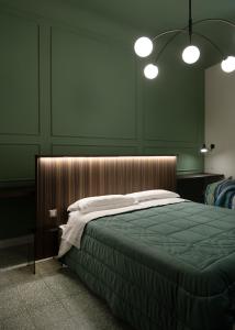 a bedroom with a bed with green walls and lights at La Martina Home in Valguarnera Caropepe