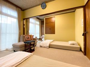 a bedroom with two beds and a chair and a window at toya町家-chitose in Toyama