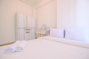 a white bedroom with a large bed with towels on it at Comfort and Nice 2BR at Tokyo Riverside PIK 2 Apartment By Travelio in Rawalembang