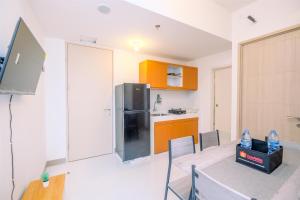 a kitchen with a table and a stainless steel refrigerator at Comfort and Nice 2BR at Tokyo Riverside PIK 2 Apartment By Travelio in Rawalembang