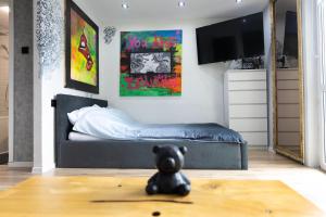 a small black teddy bear sitting on the floor in a bedroom at Art Apart in Płock