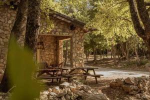 a stone cabin with a picnic table in the woods at Il Rifugio dei Briganti in Caramanico Terme