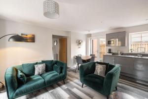 a living room with two green chairs and a kitchen at Host & Stay - Shipwright Lodge in Whitby