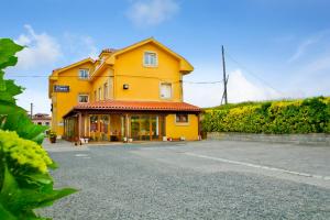 a large yellow house with a driveway in front of it at Hostería Fimar in Ubiarco