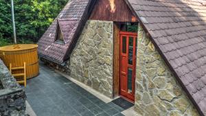a small stone building with a red door at Erdő Mélyén Házikó in Dörgicse