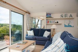 ein Wohnzimmer mit einem blauen Sofa und einem Tisch in der Unterkunft Elevated Coastal Escape - Breathtaking Views in Salcombe + 18 Fotos