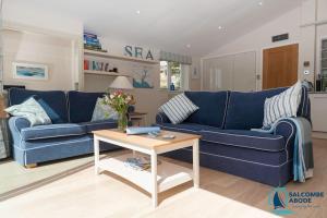 ein Wohnzimmer mit einem blauen Sofa und einem Tisch in der Unterkunft Elevated Coastal Escape - Breathtaking Views in Salcombe