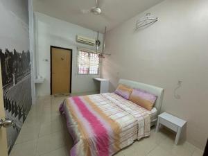 a bedroom with a bed with a striped blanket at Joyhome Homestay in Kampong Lumut Kiri +2 photos