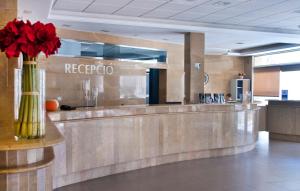 un vestíbulo con un mostrador de recepción con flores rojas en un jarrón en Hotel Bon Repos, en Calella