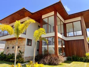 a house with large glass windows and palm trees at Casa Malibu_Praia do Forte in Mata de Sao Joao