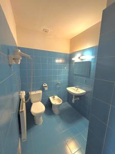 a blue bathroom with a toilet and a sink at Hostel Nuove Frontiere in Nysa +11 photos
