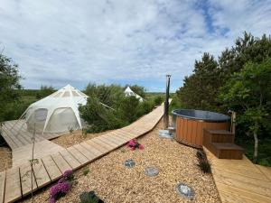 TåbelにあるAgger Glamping - Klithedenの木の道に立つ白いテントと温水浴槽