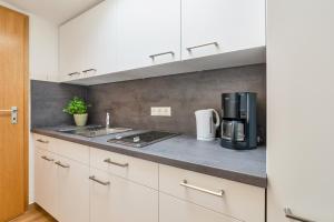 a kitchen with white cabinets and a counter top at Haus Kehrwieder 9 Bungalow in Grömitz +2 photos