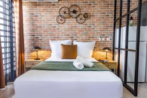 a bedroom with a large white bed with a brick wall at Le Loft industriel à la Zac Hibiscus - Terrasse in Trou Biron