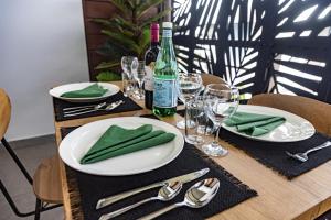 a wooden table with white plates and wine glasses at Le Loft industriel à la Zac Hibiscus - Terrasse in Trou Biron +5 photos