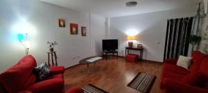 a living room with a red couch and a tv at Mgrahamhouse in Tacoronte