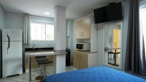 a kitchen with a refrigerator and a counter top at Residencial Dona Dina - Mestre Naro in Bombinhas
