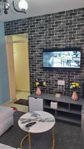 a living room with a tv and a brick wall at Gany Home Vibes - Comfy 1-bedroom apartment in Nairobi with Parking and Netflix - TRM drive in Nairobi