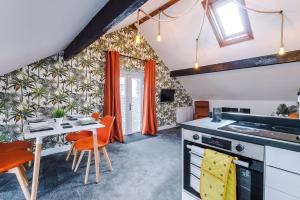a kitchen and dining room with orange chairs and a table at 'Apple Store' - Mochdre Cottages in Mochdre