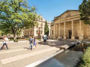 アデレードにあるGrosvenor Hotel Adelaide by Accorの建物前を歩く人々