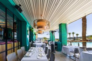 a restaurant with white tables and chairs and the ocean at Hard Rock Hotel Ibiza in Playa d'en Bossa