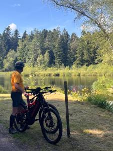 a man is standing next to a bike next to a lake at gite du Breuchin in La Longine
