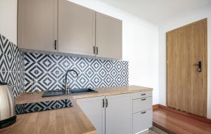 una cocina con armarios blancos y papel pintado geométrico en Beautiful Apartment In Jastarnia, en Jastarnia
