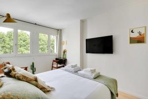 Un dormitorio con una cama grande y un televisor de pantalla plana. en Green Suites Résidence Meudon Velizy, en Meudon