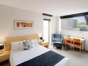 城堡山Mantra Castle Hill Sydney, an Accor Hotel的一间卧室，配有一张床、一张桌子和一把椅子 更多37张照片