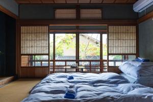 un letto grande in una stanza con una finestra di 篠山城下町ゲストハウス quolo a Tamba-sasayama