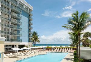 里维埃拉海滩The Singer Oceanfront Resort, Curio Collection by Hilton的一张带椅子和遮阳伞的游泳池图片