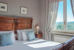 a bedroom with a bed with blue pillows and a window at B&B Casa Margot in Neive