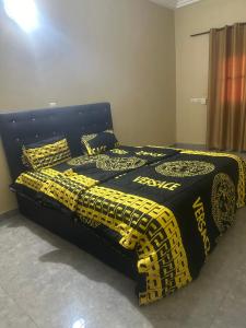 a bed with black and yellow sheets and pillows at Vhomes in Apéyémé