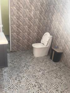 a bathroom with a toilet and a tiled floor at Vhomes in Apéyémé