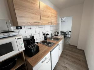 a small kitchen with a sink and a microwave at Vollausgestatte Wohnung mit, WLAN, TV in jedem Schlafzimmer, Einzelbetten, Bad, Garten in Crimmitschau
