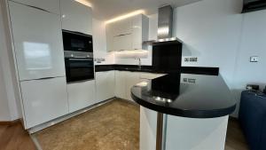 a kitchen with white cabinets and a black counter top at Ocean Spa Plaza Luxury Suite in Gibraltar
