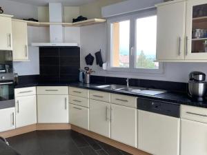 a kitchen with white cabinets and a sink and a window at Maison avec jardin Gérardmer L'AUTOUR in Gérardmer