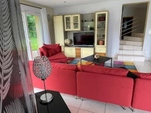 a living room with a red couch and a tv at Maison avec jardin Gérardmer L'AUTOUR in Gérardmer +23 photos