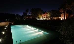 - une piscine la nuit avec une maison en arrière-plan dans l'établissement Tenuta Ponziani - Griffin's Resort, à Morrano