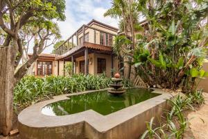 a house with a pond in front of a house at Singa Lodge - Lion Roars Hotels & Lodges in Port Elizabeth