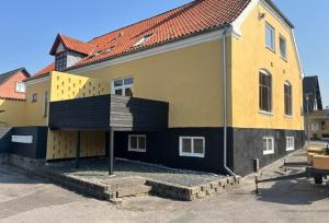 a large yellow and black house with a porch at Folsted - Værelse 101 med eget badeværelse og fri parkering in Bindslev