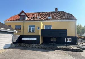 a large yellow house with a black garage at Folsted - Værelse 101 med eget badeværelse og fri parkering in Bindslev