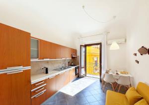 a kitchen with wooden cabinets and a dining table at Solemar Sicilia - Casa Emma in Porticello
