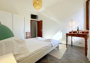 a white bedroom with a bed and a desk at Solemar Sicilia - Casa Emma in Porticello