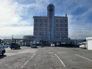 ein großes Gebäude mit auf einem Parkplatz geparkten Autos in der Unterkunft Hotel Marsh Land in Kushiro