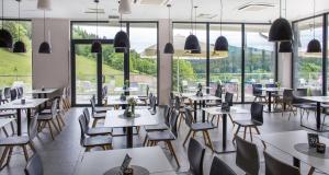 ein Restaurant mit Tischen und Stühlen und großen Fenstern in der Unterkunft Aparthotel Apartamenty Czarna Góra 107 in Heudorf