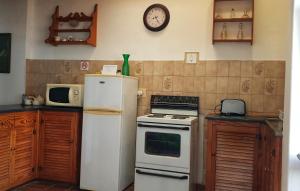 a kitchen with a refrigerator and a clock on the wall at Camdeboo Cottages in Graaff-Reinet
